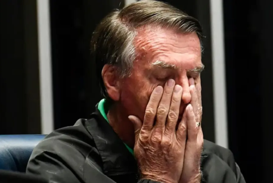 Jair Bolsonaro (PL) com as mãos no rosto, em close, de olhos fechados, sério