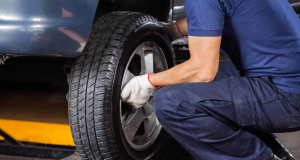 Homem trocando pneu de carro, agachado