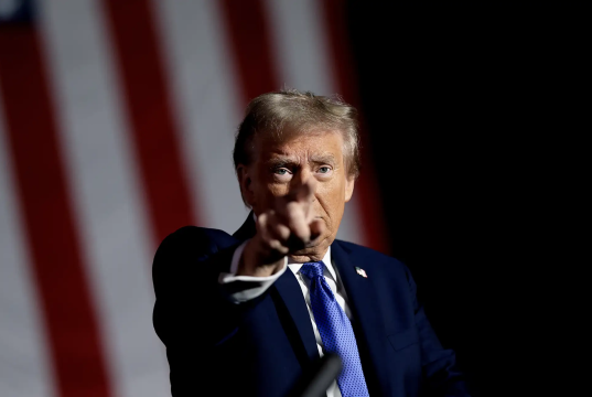 Donald Trump apontando pra frente, sério