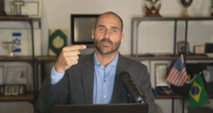 deputado federal Eduardo Bolsonaro (PL-SP) falando e apontando para si mesmo, sério, olhando para a câmera, de roupa social
