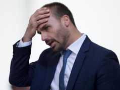 O deputado federal Eduardo Bolsonaro (PL-SP) sério, com a mão na cabeça, cabisbaixo, de perfil