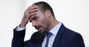 O deputado federal Eduardo Bolsonaro (PL-SP) sério, com a mão na cabeça, cabisbaixo, de perfil
