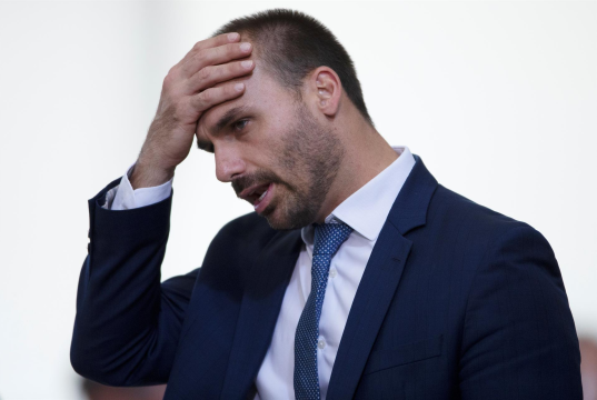 O deputado federal Eduardo Bolsonaro (PL-SP) sério, com a mão na cabeça, cabisbaixo, de perfil