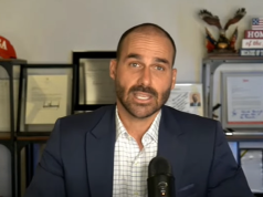 O deputado federal Eduardo Bolsonaro (PL-SP) falando para a câmera, sério, de roupa formal azul e branca