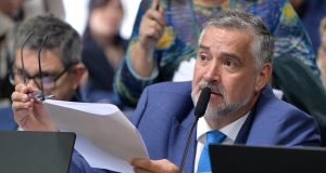 deputado Paulo Pimenta (PT-RS) falando em microfone e segurando papel, sério, sem olhar para a câmera