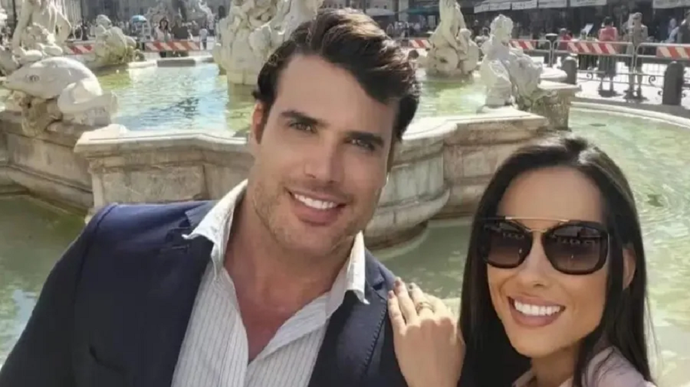 O empresário Renê da Silva Nogueira Júnior e a esposa, Ana Paula Lamego Balbino Nogueira, abraçados, sorrindo lado a lado perto de fonte, ela de óculos escuros