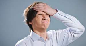 Rapaz com os olhos fechados e mão no rosto, fazendo careta