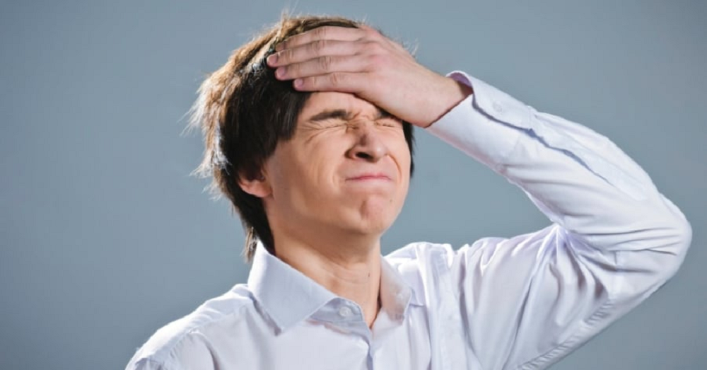 Rapaz com os olhos fechados e mão no rosto, fazendo careta