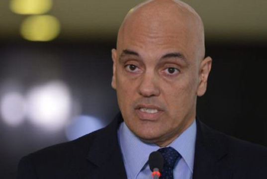 Alexandre de Moraes falando, sério, sem olhar para a câmera, em close, de terno e gravata