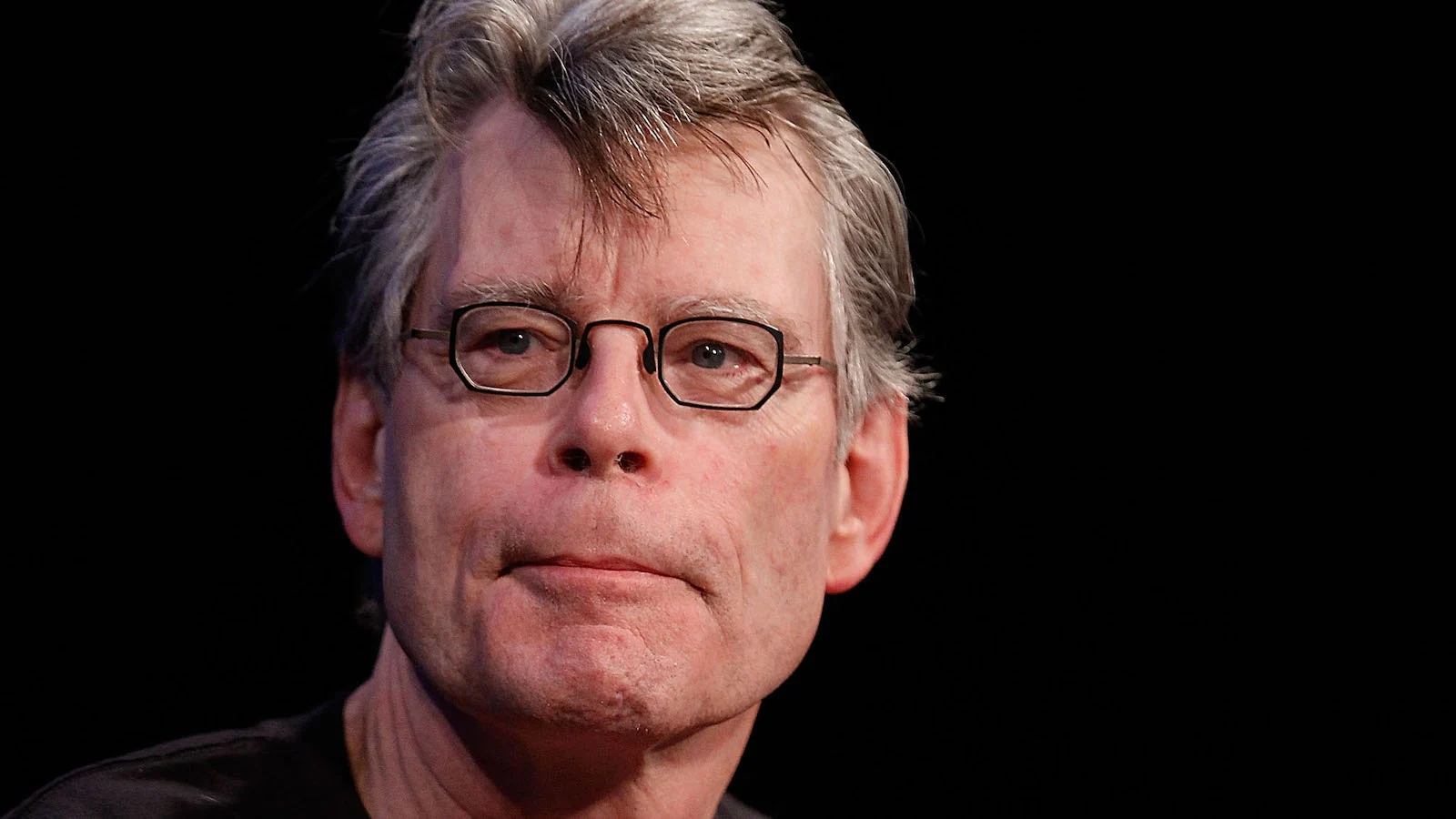 Stephen King em close, sério, de óculos