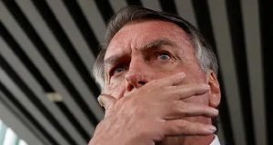ex-presidente Jair Bolsonaro (PL) com a mão no rosto e expressão de medo, em close, em foto feita de baixo, ele sem olhar para a câmera