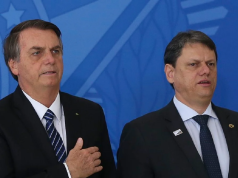 Jair Bolsonaro e Tarcísio de Freitas em pé, lado a lado, sérios, o primeiro com a mão no peito