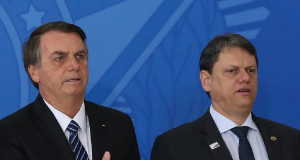 Jair Bolsonaro e Tarcísio de Freitas em pé, lado a lado, sérios, o primeiro com a mão no peito