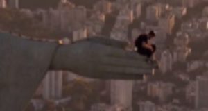 Homem sentado em uma das mãos do Cristo Redentor