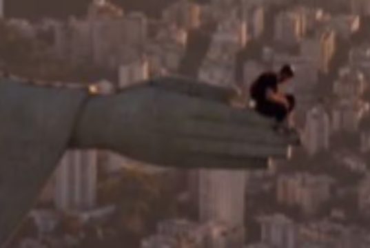 Homem sentado em uma das mãos do Cristo Redentor
