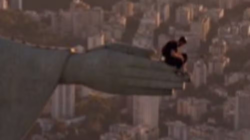 Homem sentado em uma das mãos do Cristo Redentor