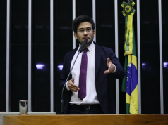 O deputado Kim Kataguiri (União-SP) em pé, falando em microfone e gesticulando, na Câmara dos Deputados