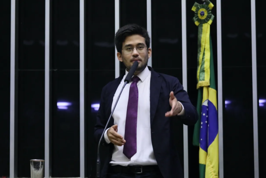 O deputado Kim Kataguiri (União-SP) em pé, falando em microfone e gesticulando, na Câmara dos Deputados