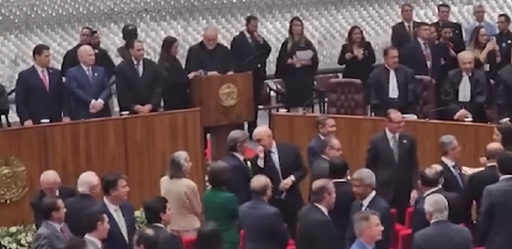 os ministros Alexandre de Moraes e Luiz Fux cochichando em pé, lado a lado