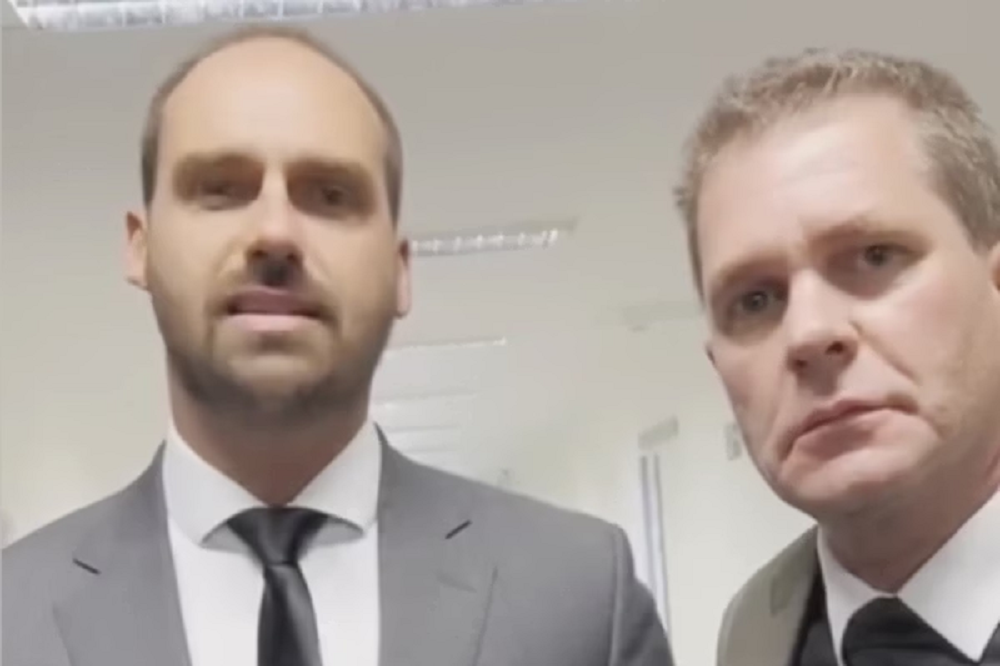 Eduardo Bolsonaro e Luiz Felipe Pereira da Cunha sérios e olhando para a câmera