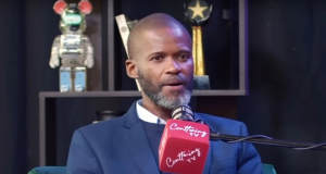 O pastor sul-africano Joshua Mhlakela falando em microfone, sério, sem olhar para a câmera