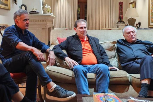 O deputado Aécio Neves, o relator da anistia, Paulinho da Força, e o ex-presidente Michel Temer sentados lado a lado em poltrona e sofá, sérios