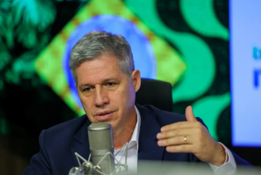 Paulo Teixeira, ministro do Desenvolvimento Agrário e Agricultura Familiar, sério, falando em microfone e gesticulando sem olhar para a câmera