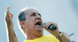O pastor Silas Malafaia gritando em microfone e gesticulando, de camiseta amarela pedindo Justiça
