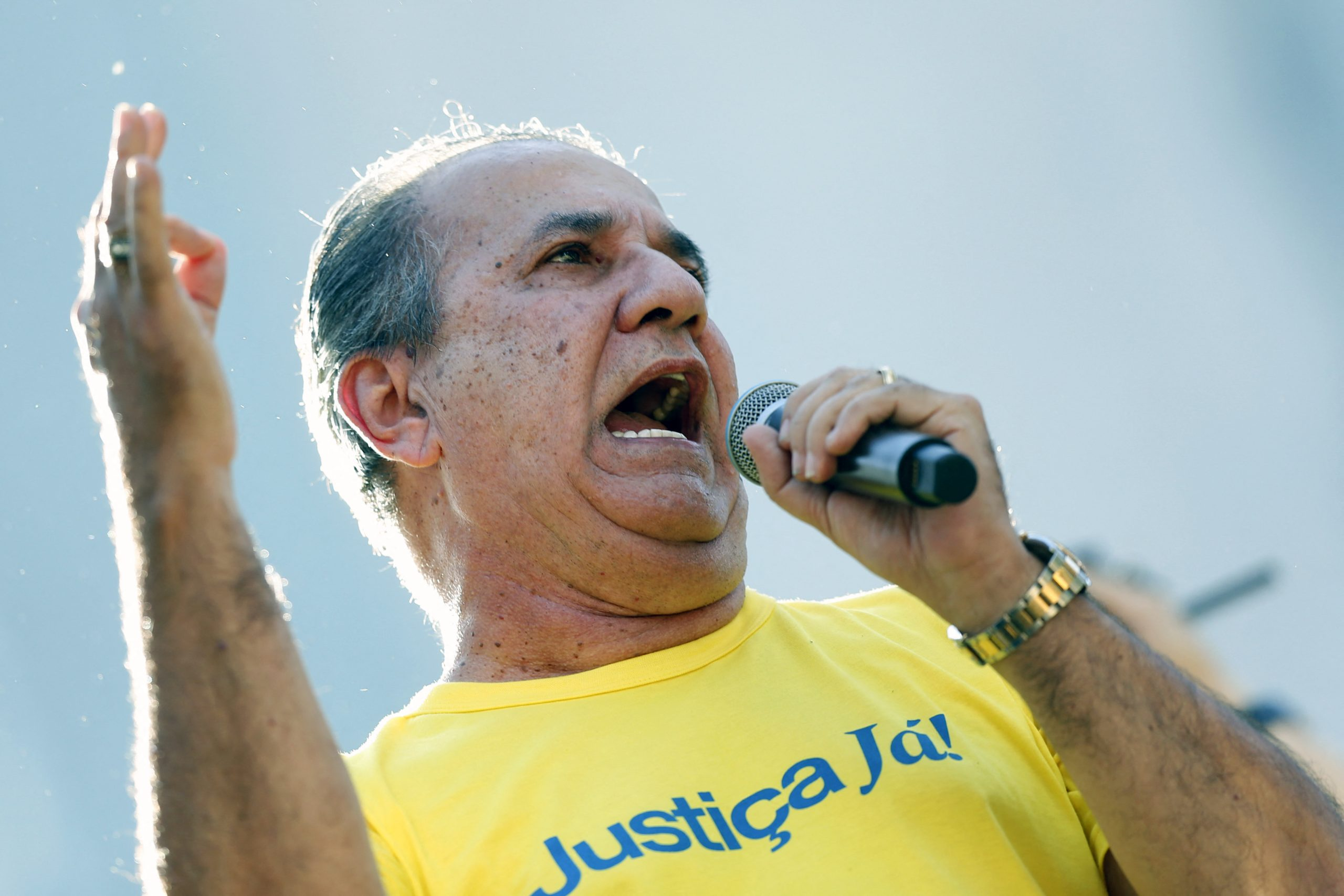 O pastor Silas Malafaia gritando em microfone e gesticulando, de camiseta amarela pedindo Justiça
