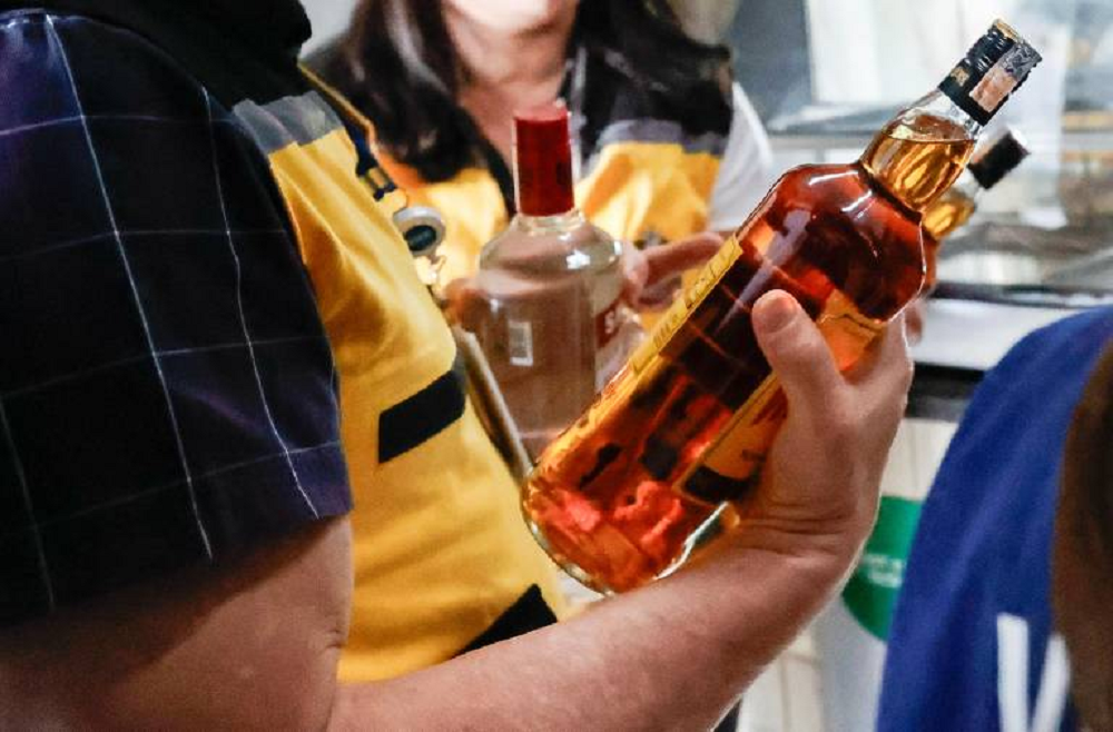 Pessoas segurando garrafas de bebida alcoólica
