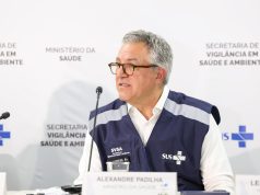 O ministro da Saúde, Alexandre Padilha, falando em microfone sem olhar para a câmera, de óculos