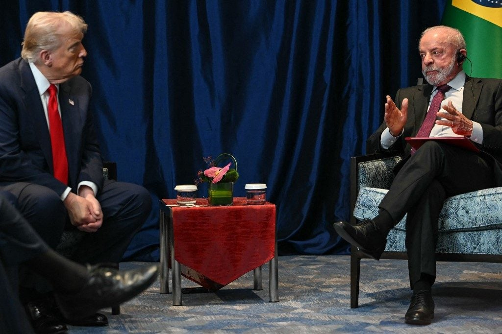 Donald Trump e Lula conversando, sentados frente a frente