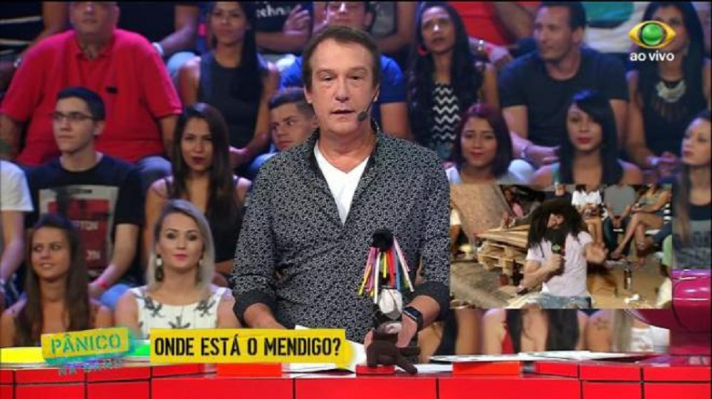 Emílio Surita na época do Pânico na Band, em pé, falando para a câmera, com a plateia atrás