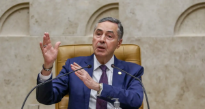 O ministro Luís Roberto Barroso, do STF (Supremo Tribunal Federal), falando e gesticulando, sentado, sem olhar para a câmera