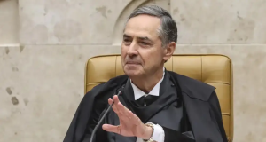 O ministro do STF Luís Roberto Barroso sorrindo e olhando para o lado, acenando