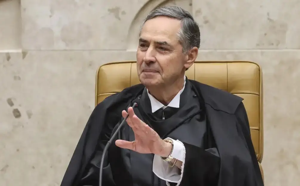 O ministro do STF Luís Roberto Barroso sorrindo e olhando para o lado, acenando