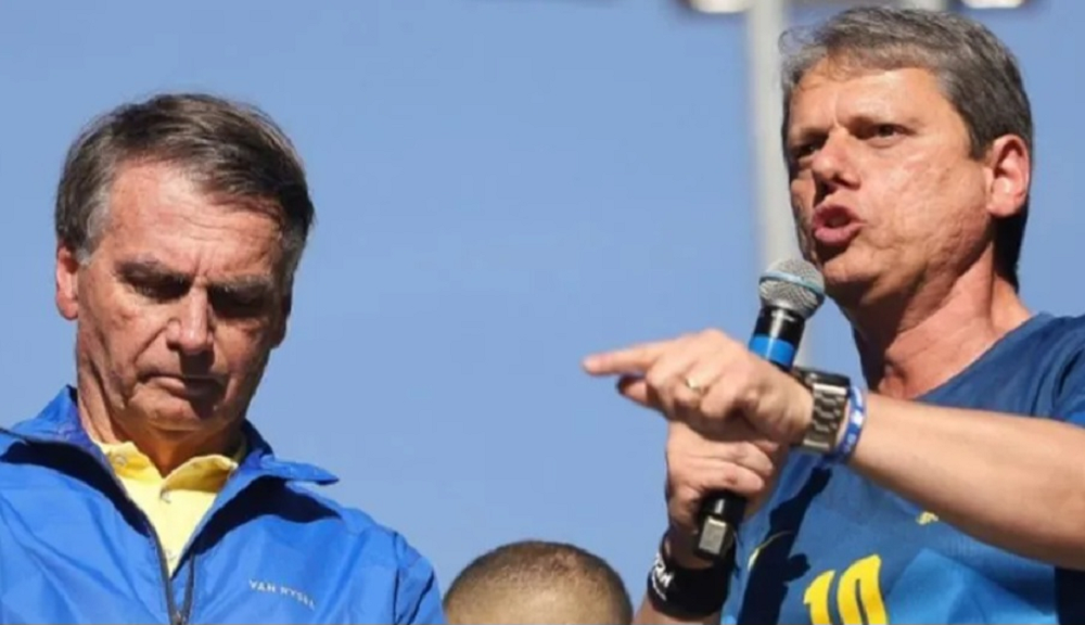 Jair Bolsonaro cabisbaixo e Tarcísio de Freitas falando em microfone