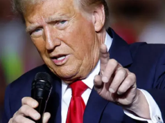 Donald Trump, presidente dos EUA, falando em microfone e apontando pra frente, em close