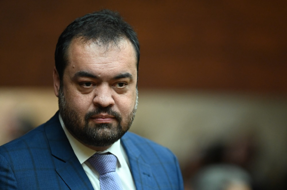 Claudio Castro sério, no canto esquerdo da foto, sem olhar para a câmera, de roupa social azul