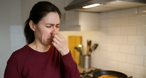 Mulher fazendo careta e tapando o nariz perto de fogão