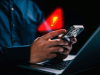 Mão mexendo em celular com sinal de alerta em arte
