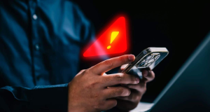 Mão mexendo em celular com sinal de alerta em arte