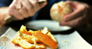 Pessoa descascando laranja, só mãos aparecendo