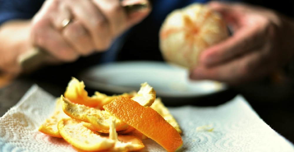 Pessoa descascando laranja, só mãos aparecendo