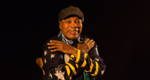 cantor Milton Nascimento sorrindo para a câmera se abraçando