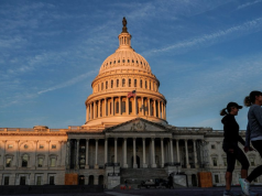 Senado dos Estados Unidos em dia de céu azul, com duas mulheres caminhando no canto direito da foto
