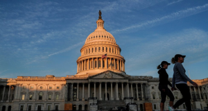 Senado dos Estados Unidos em dia de céu azul, com duas mulheres caminhando no canto direito da foto