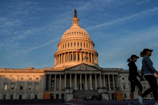 Senado dos Estados Unidos em dia de céu azul, com duas mulheres caminhando no canto direito da foto