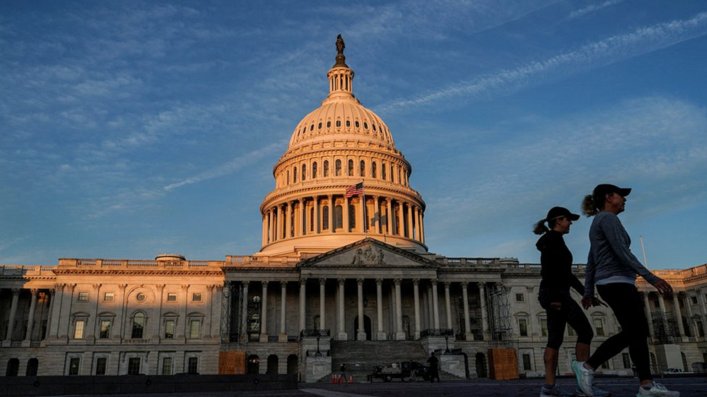 Senado dos Estados Unidos em dia de céu azul, com duas mulheres caminhando no canto direito da foto