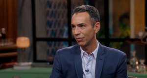 César Tralli no Conversa com Bial, de roupa social azul marinho, falando sem olhar para a câmera